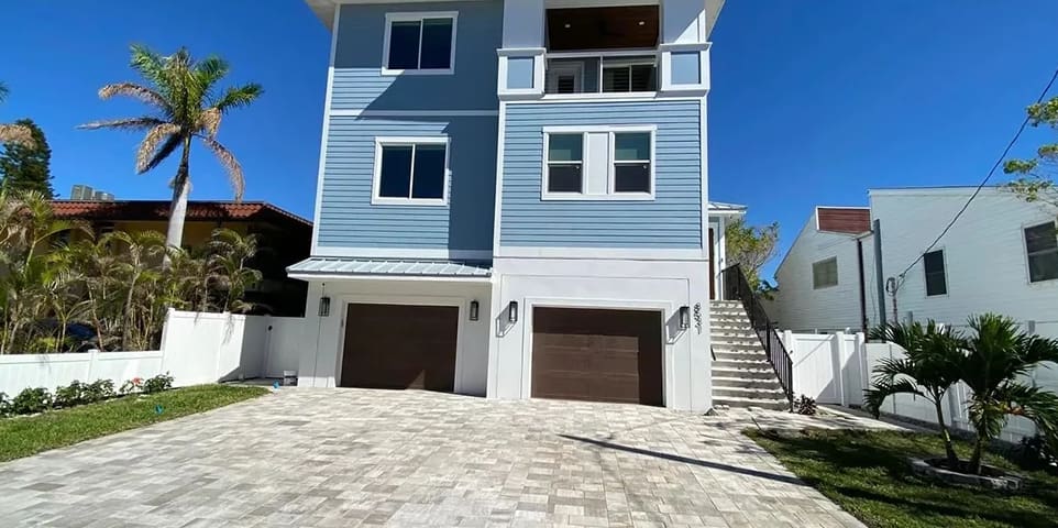 A blue house with two garage doors and steps leading up to it.