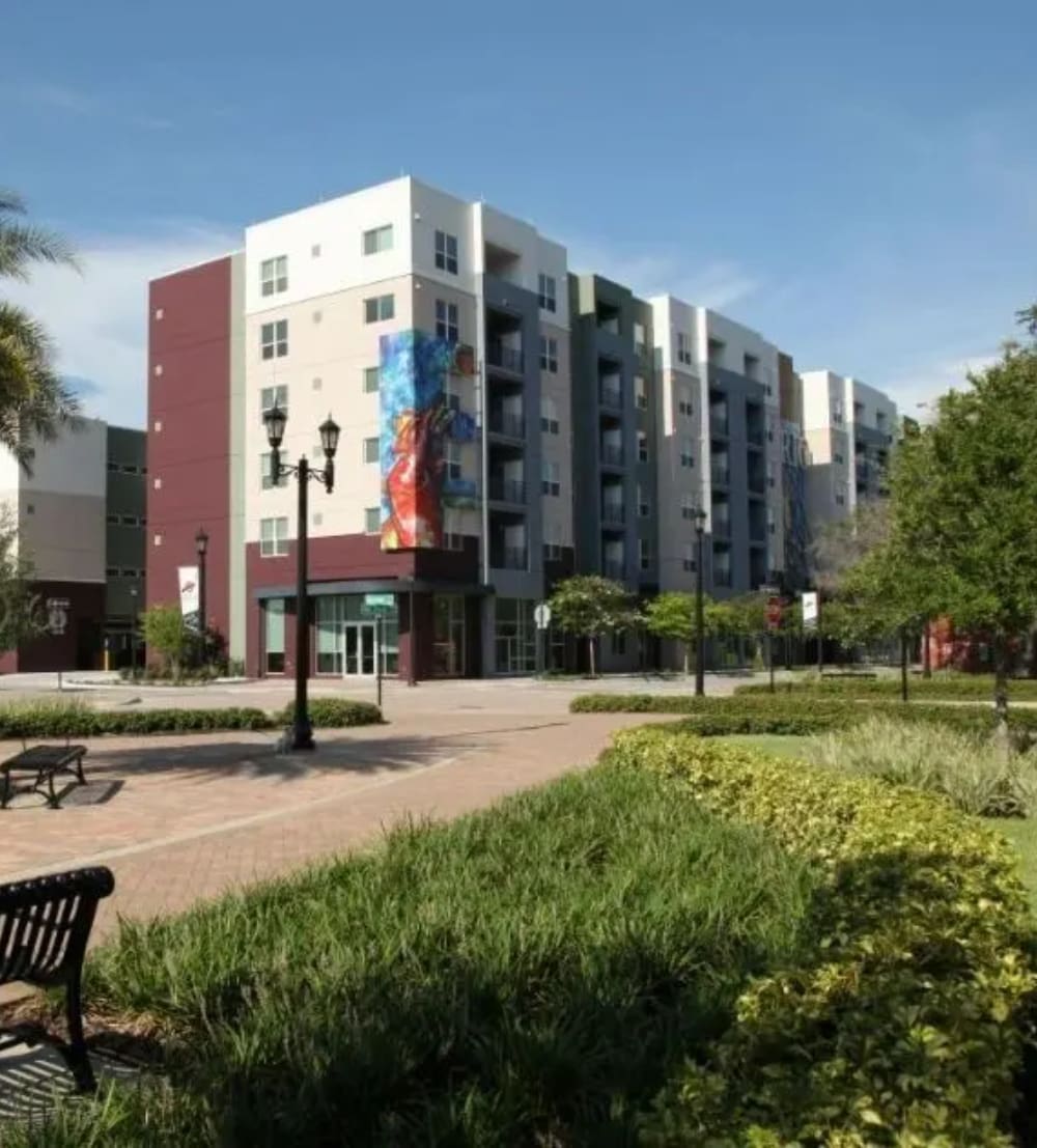 A park with benches and trees in front of a building.